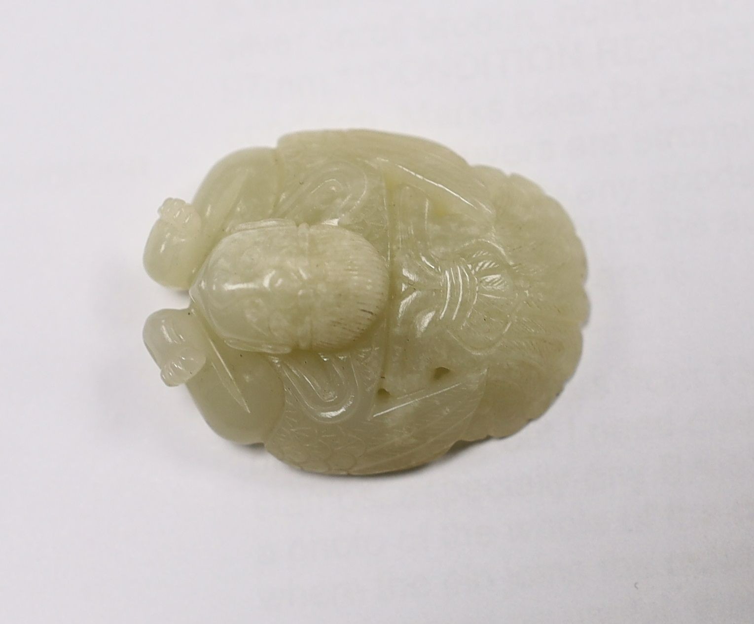 A Chinese pale celadon jade mount carved as a mythical half-man half-bird creature, 18th/19th century, 3.8cm high